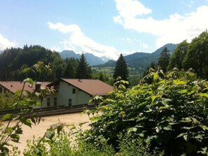 Un edificio con tetto rosso, immerso nel verde e con montagne sullo sfondo.