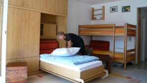 Un dormitorio compacto con una cama individual, un armario de madera y una cama litera.