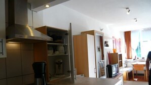 Una cocina compacta con estufa, cafetera y armarios.
