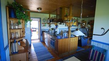 A spacious kitchen with wooden cabinets, a central island, and a dining area with a striped sofa.