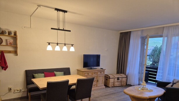 A modern living room with a wooden dining table, black chairs, a sofa, a television, and a wooden chest of drawers. - Falkenberg Wh 218 by Interhome (Oberstdorf)