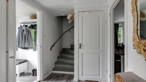 A hallway with a staircase, a coat rack with jackets, and a mirror on the wall. - Vacation home Ida by Interhome (Mariannelund)