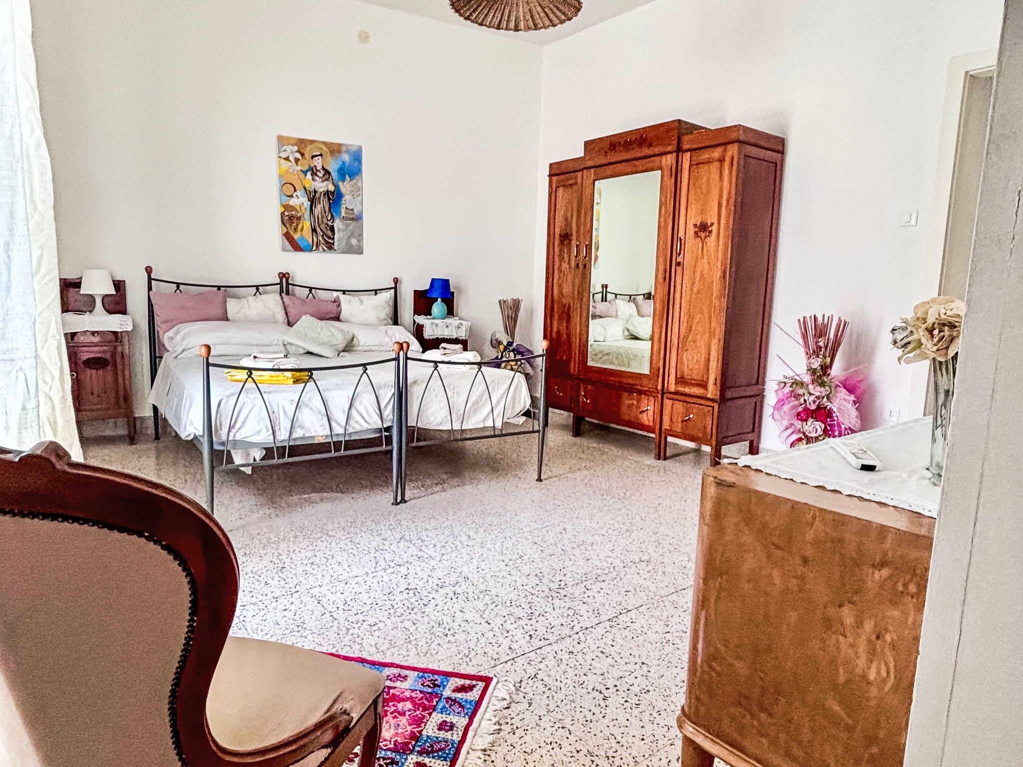 Een slaapkamer met een bed, een houten garderobe, een bureau en een stoel.