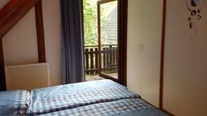 A bedroom with a bed, a radiator, and a door leading to an outdoor balcony. - Vacation home Tindy by Interhome (Frielendorf)