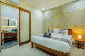 A bedroom with a wooden bed, a marble bedside table, a built-in sink, and a stone-patterned wall.
