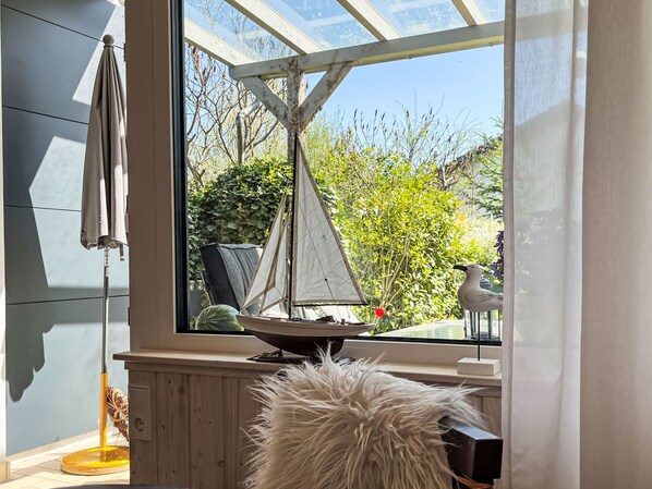 Een kamer met een groot raam, een model zeilboot en een pluizig wit voorwerp.