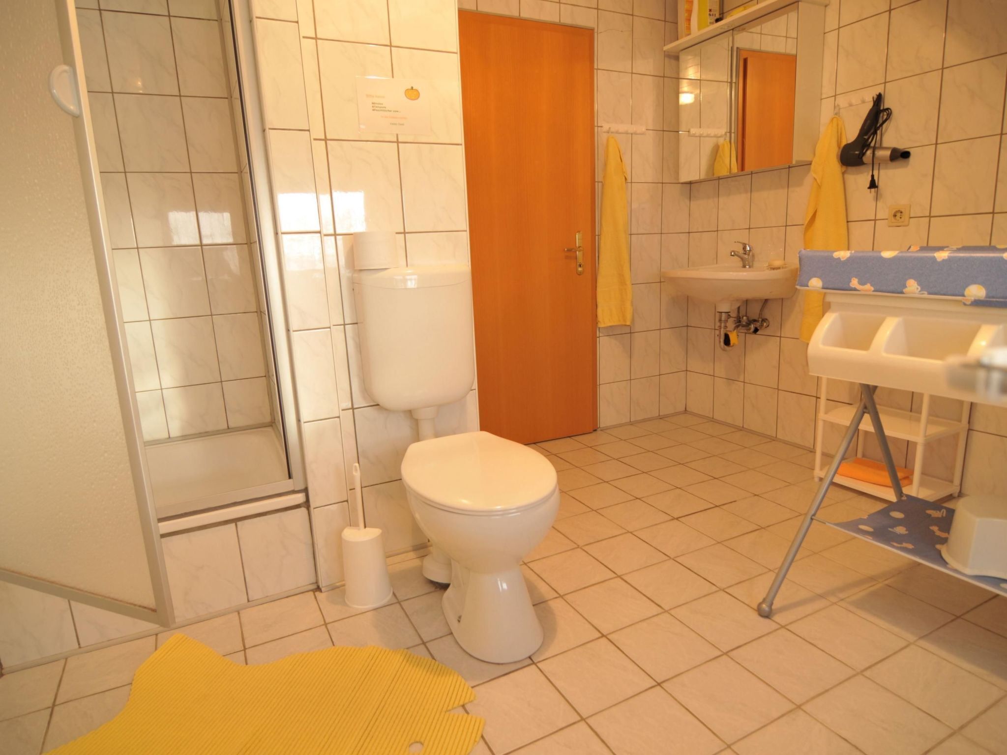 A bathroom with a toilet, sink, and shower area.