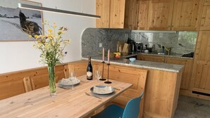 Ein Holztisch mit Stühlen, eine Blumenvase und eine Weinflasche.