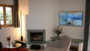 Ein Wohnzimmer mit Kamin, einem Gemälde an der Wand und einem modernen Sessel.