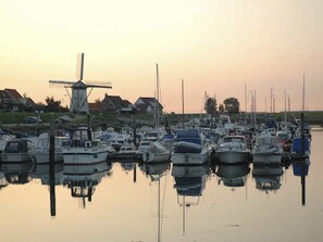 A marina with multiple boats docked, a windmill, and houses in the background. - Ferienhaus Buurtweg 185 by Interhome (Stavenisse)
