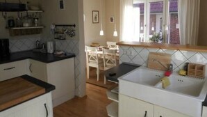 A kitchen with a wooden countertop, white cabinets, and a window with curtains. - in Norden mit großem Garten by Interhome (Norden)