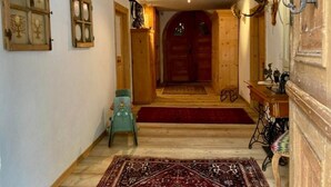 A wooden interior hallway with a red carpet, a small blue chair, and a patterned rug. - Chesa Robbi S-chanf by Interhome (S-chanf)