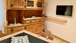 A wooden dining area with a table, chairs, and a TV mounted on the wall. - Chesa Robbi S-chanf by Interhome (S-chanf)