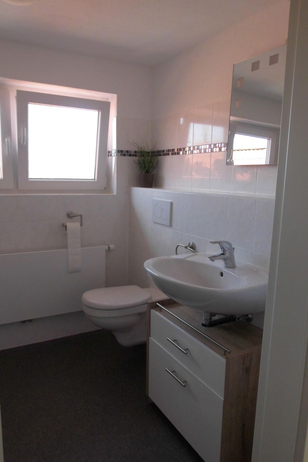 Une salle de bain avec des toilettes, un lavabo et une fenêtre.