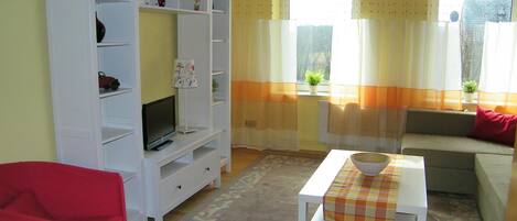 A living room with a white entertainment unit, a television, a sofa, and a coffee table.