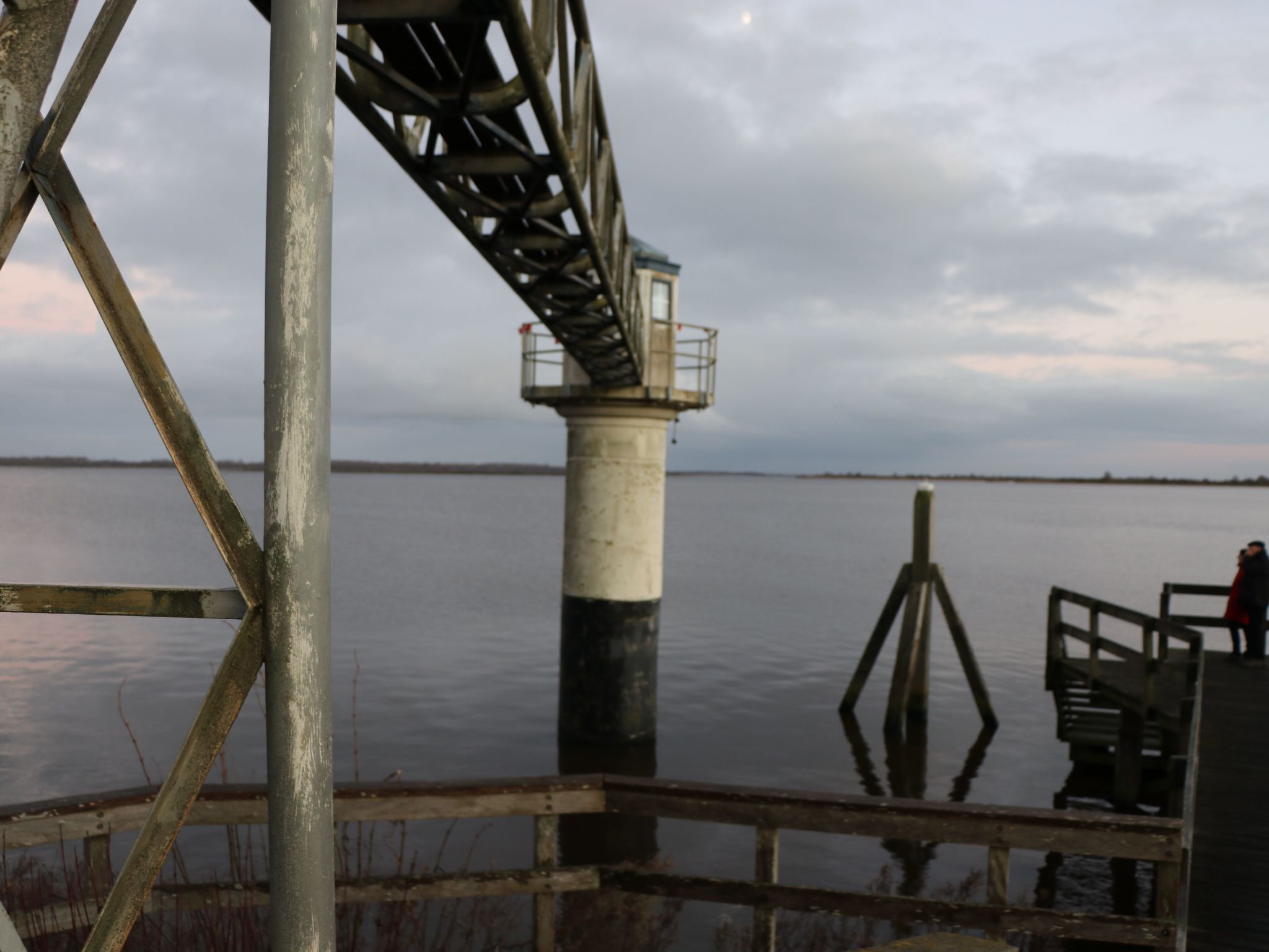 A lighthouse structure with a metal framework and a white and black painted tower.