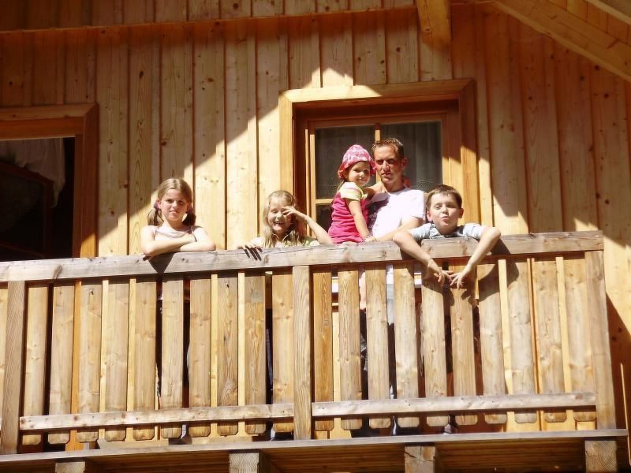 Un balcon en bois avec une balustrade, une fenêtre et une porte.
