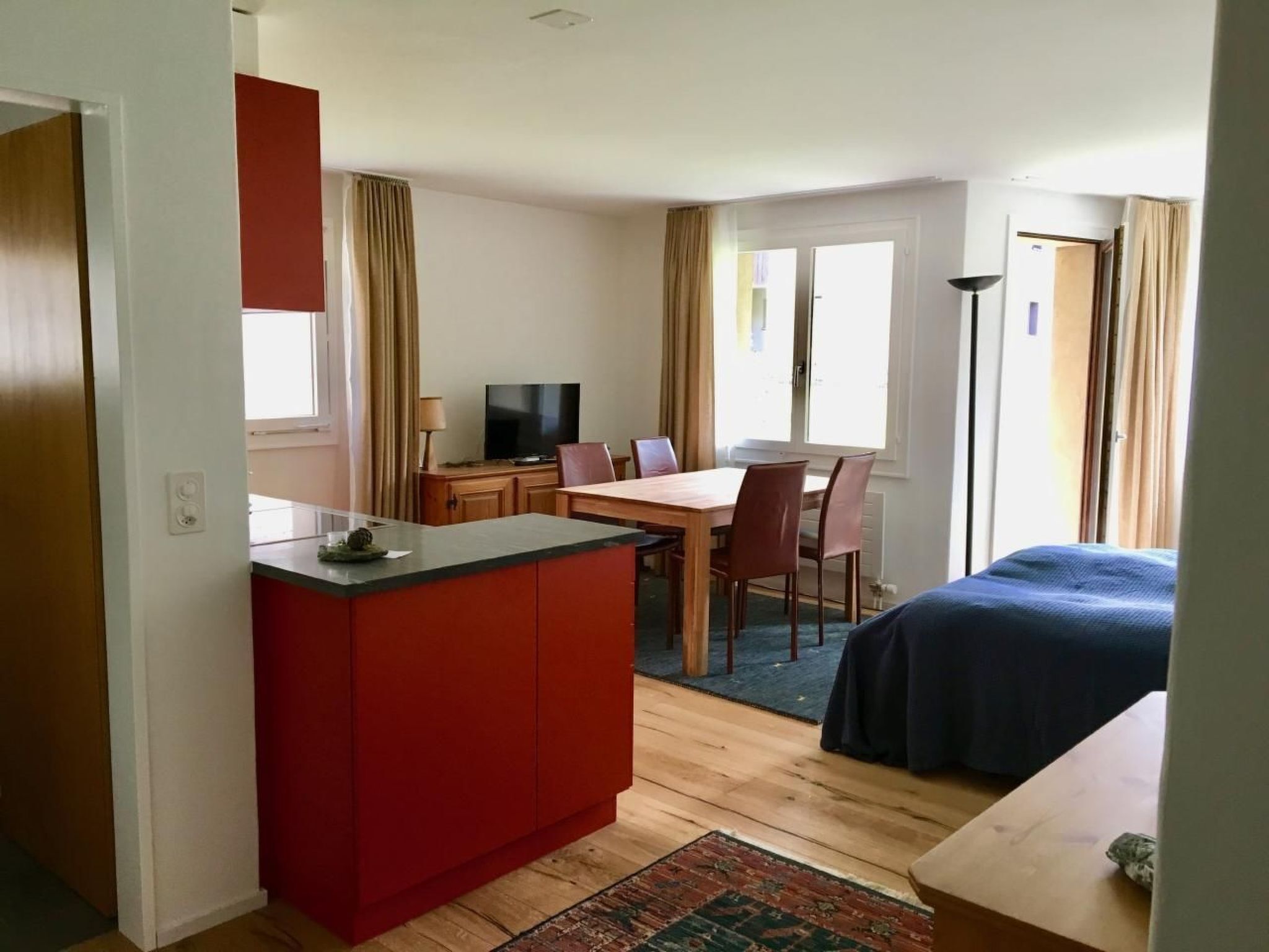 A compact hotel room with a kitchenette, a dining area, and a bed.