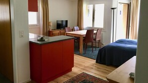 Ein kleines Hotelzimmer mit Küchenzeile, Essbereich und Bett.