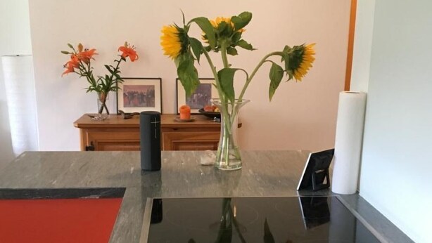 Eine Küche mit schwarzer Arbeitsplatte, einer Blumenvase und einem Holztisch mit Bilderrahmen und Kerze.