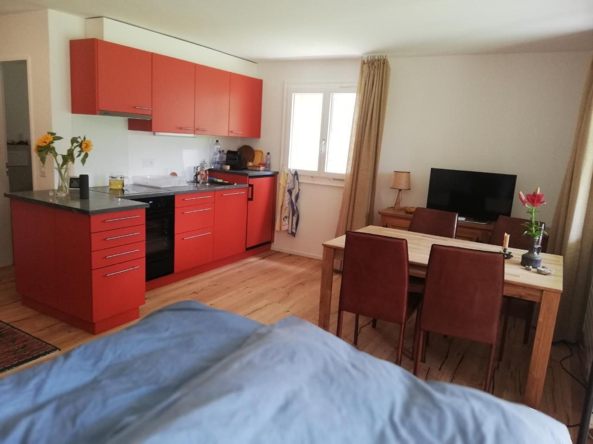 Ein kompaktes Hotelzimmer mit Küchenzeile, Essbereich und einem Bett.