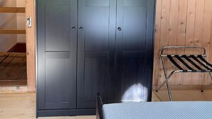 A bedroom with a bed, a dark wardrobe, and a wooden wall.