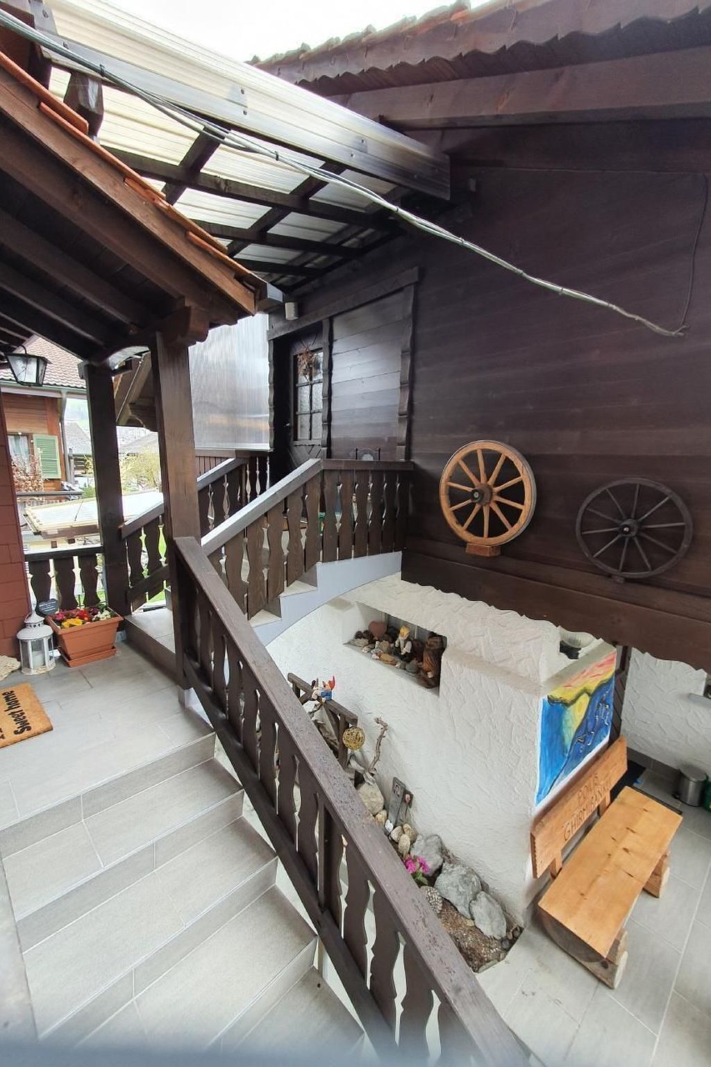 A wooden staircase with a railing, a wooden bench, and a wall with two wooden wheels.