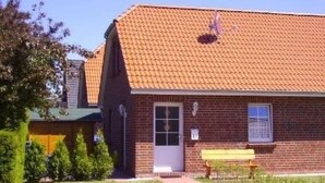 Ein Gebäude aus Backsteinen mit Ziegeldach, einer Tür und einer Bank im Vordergrund.