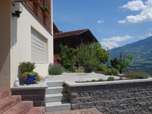Una casa amb garatge, escales que condueixen a l'entrada i vistes a les muntanyes al fons.