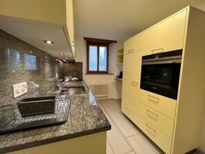 Een koelkast, een oven, een vaatwasser, kookgerei, borden en bestek