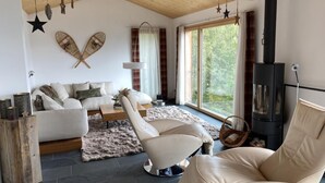 Una sala de estar moderna con un sofá, sillas, una chimenea y un ventanal grande.