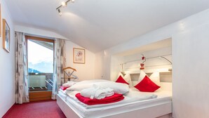 A modern hotel room with a large bed, red and white bedding, a balcony with a view, and a minimalist decor. - "Idylle by Interhome (Walchsee)