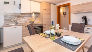 A modern kitchen with a stone backsplash, wooden cabinets, and a dining area with a table set for two. - "Idylle by Interhome (Walchsee)