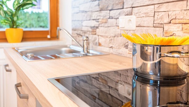 A modern kitchen with a stone backsplash, stainless steel appliances, and a window with a view of greenery. - "Idylle by Interhome (Walchsee)