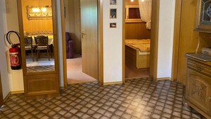 Een kleine kamer met een vloer met patroon, een bed, een tafeltje en een kast.