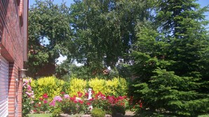 A garden with a statue, a bird sculpture, and a variety of flowers. - mit umfriedetem Garten und Terrassen by Interhome (Greetsiel)