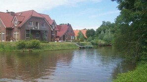 A riverside view with houses and a dock. - mit umfriedetem Garten und Terrassen by Interhome (Greetsiel)