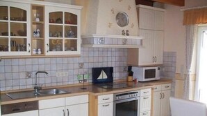 A kitchen with white cabinets, a microwave, an oven, and a sink. - mit umfriedetem Garten und Terrassen by Interhome (Greetsiel)