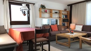 A modern living room with a sofa, a dining table, a coffee table, and a bookshelf. - Chesa Arettas by Interhome (Bever)