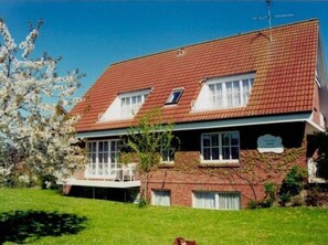 A two-story building with a red-tiled roof, a balcony, and a sign indicating it is a guesthouse. - "Rosa Canina",W6 by Interhome (Kellenhusen)