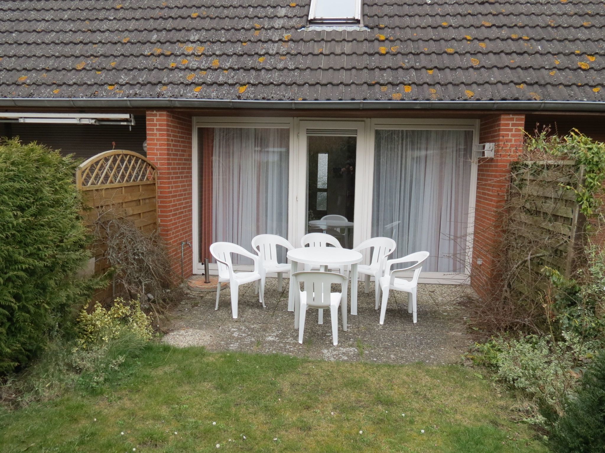 Ein Haus mit einer Terrasse, komplett mit Tisch und Stühlen.