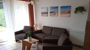 A living room with a sofa, a small table with a plant, and three framed pictures on the wall. - Vacation home Körner by Interhome (Dahme)