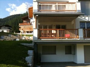 A two-story building with a balcony, a garage, and a mountainous backdrop. - Fewo mit Bergblick by Interhome (Savognin)