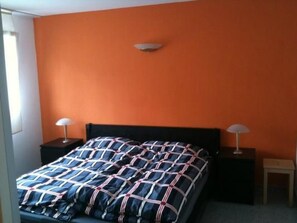A bedroom with an orange wall, a black bed frame, and two bedside lamps. - Fewo mit Bergblick by Interhome (Savognin)