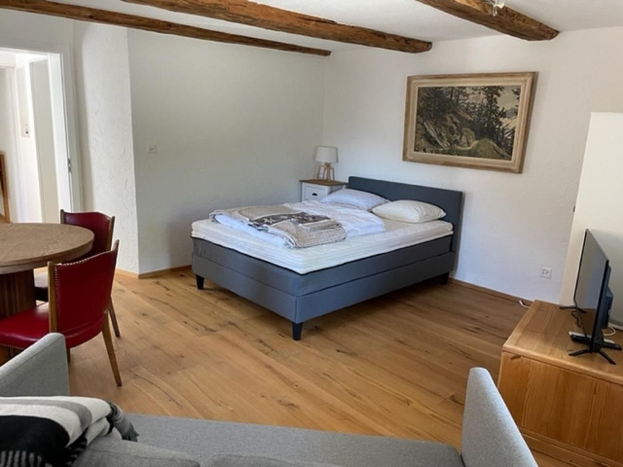 Una camera da letto con un letto, una scrivania, una sedia e un quadro appeso al muro.