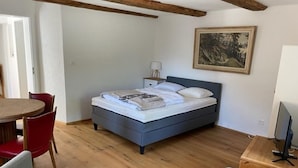 Un dormitorio con cama, escritorio, silla y un cuadro en la pared.