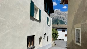 Una calle estrecha flanqueada por edificios, con una montaña al fondo y cielo despejado.