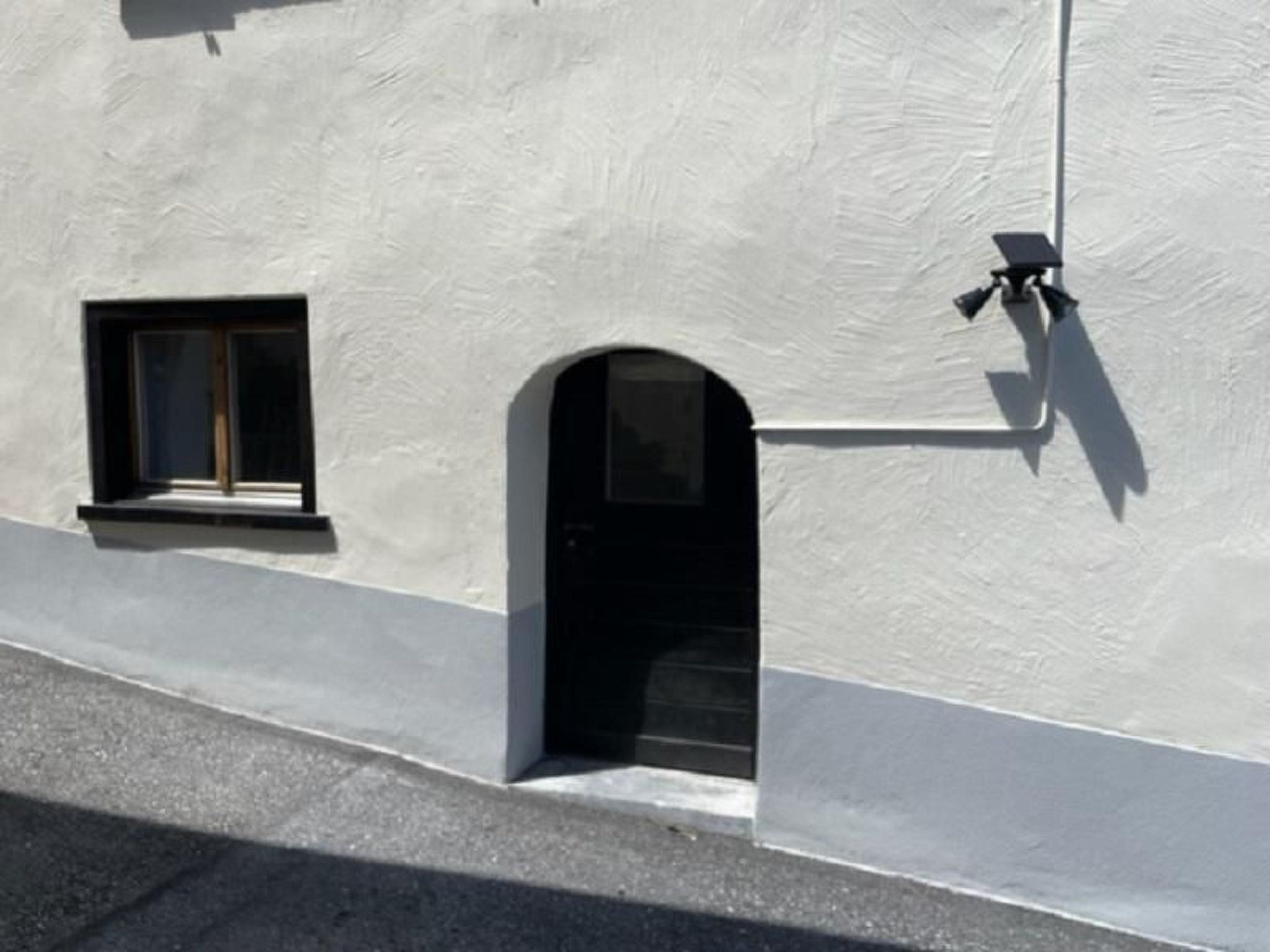 A building facade with a white exterior, a small window, and a door.