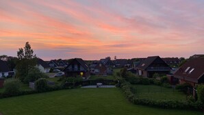Un quartier résidentiel avec des maisons, une pelouse verdoyante et un ciel au coucher du soleil.