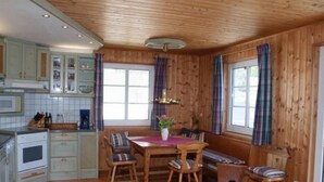 Tunnelmallinen, mökkityylinen keittiö, jossa on puuseinät ja ruokailutila.